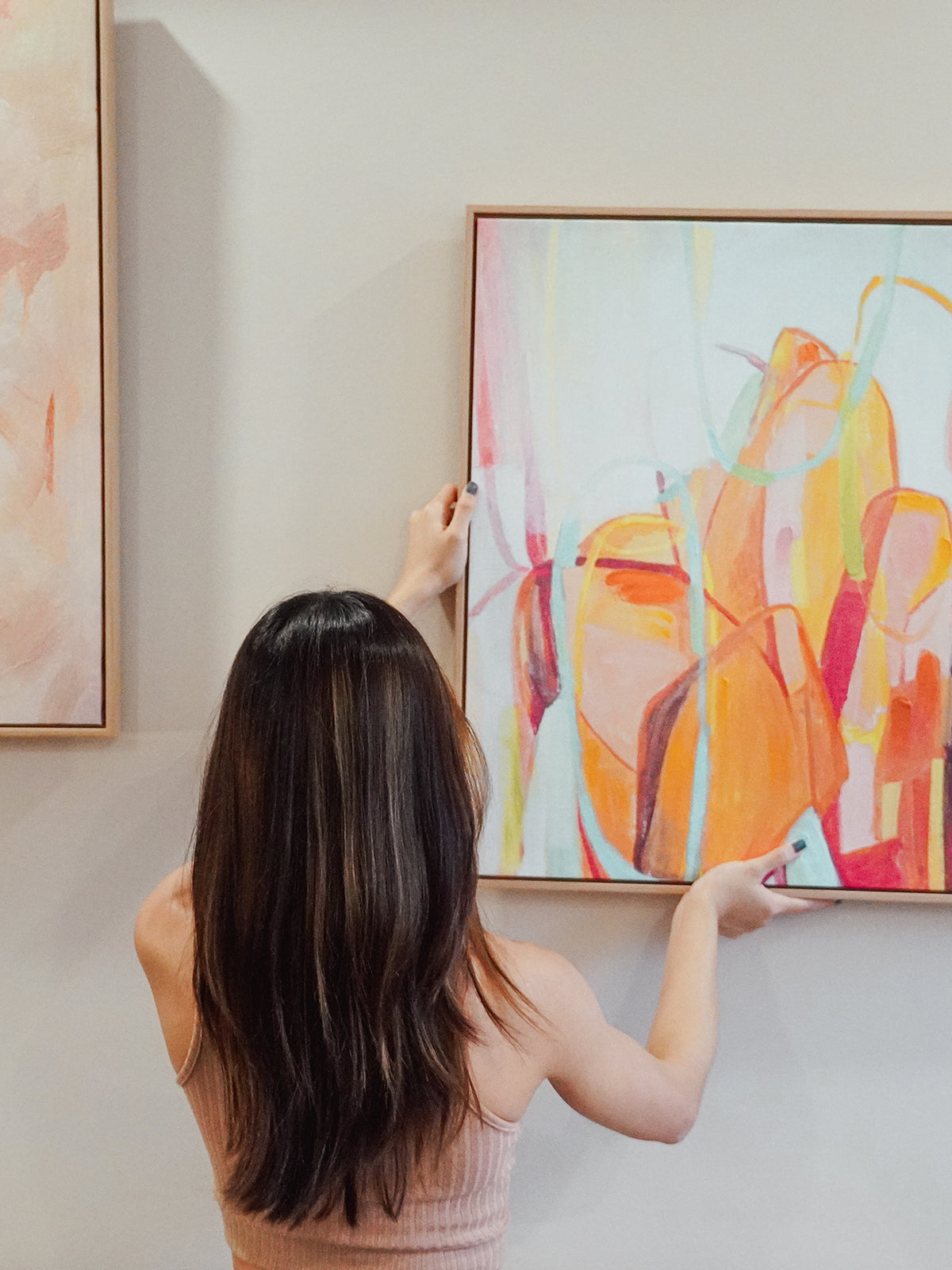 girl hanging wall art painting at home